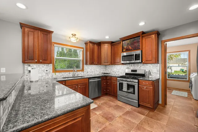 a kitchen with stainless steel appliances granite countertop a refrigerator stove and microwave
