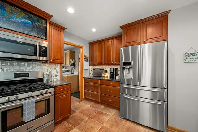 a kitchen with stainless steel appliances granite countertop a sink and wooden cabinets