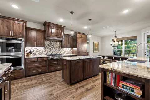 a kitchen with kitchen island granite countertop a sink stove and refrigerator