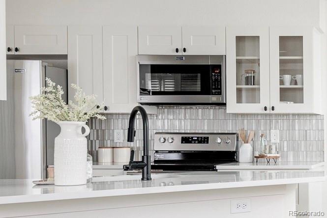 10754 West 107th Circle Westminster, CO 80021 - Photo 12 of 24 a kitchen with stainless steel appliances kitchen island granite countertop a stove and a white cabinets
