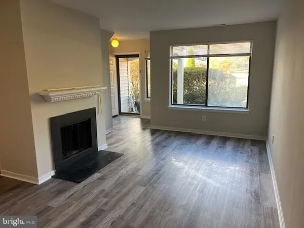 an empty room with wooden floor fireplace and windows