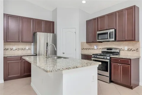 a kitchen with granite countertop a stove sink and microwave