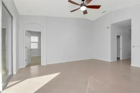 a view of an empty room with a chandelier fan