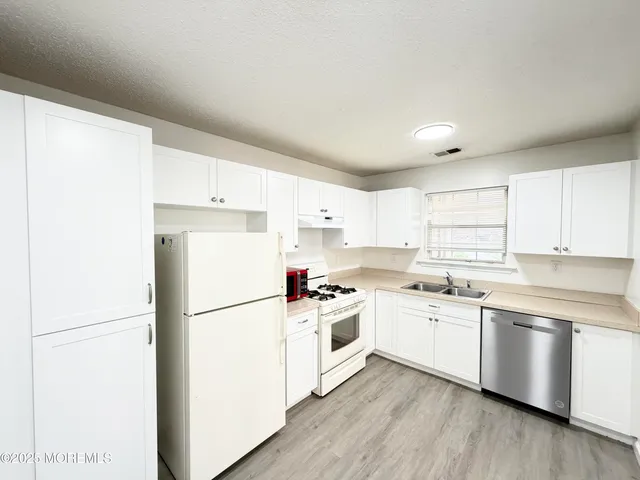 a kitchen with a white cabinets and wooden floor