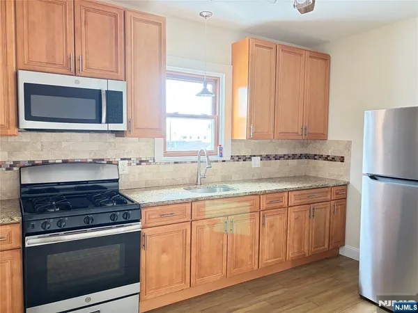 a kitchen with stainless steel appliances granite countertop a stove a sink and a refrigerator