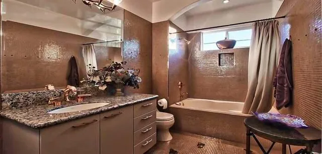 a bathroom with a granite countertop toilet a sink a mirror a bathtub and shower