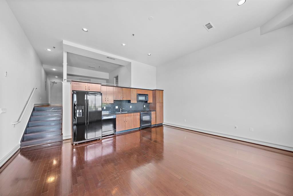 a room with stainless steel appliances wooden floor and staircase