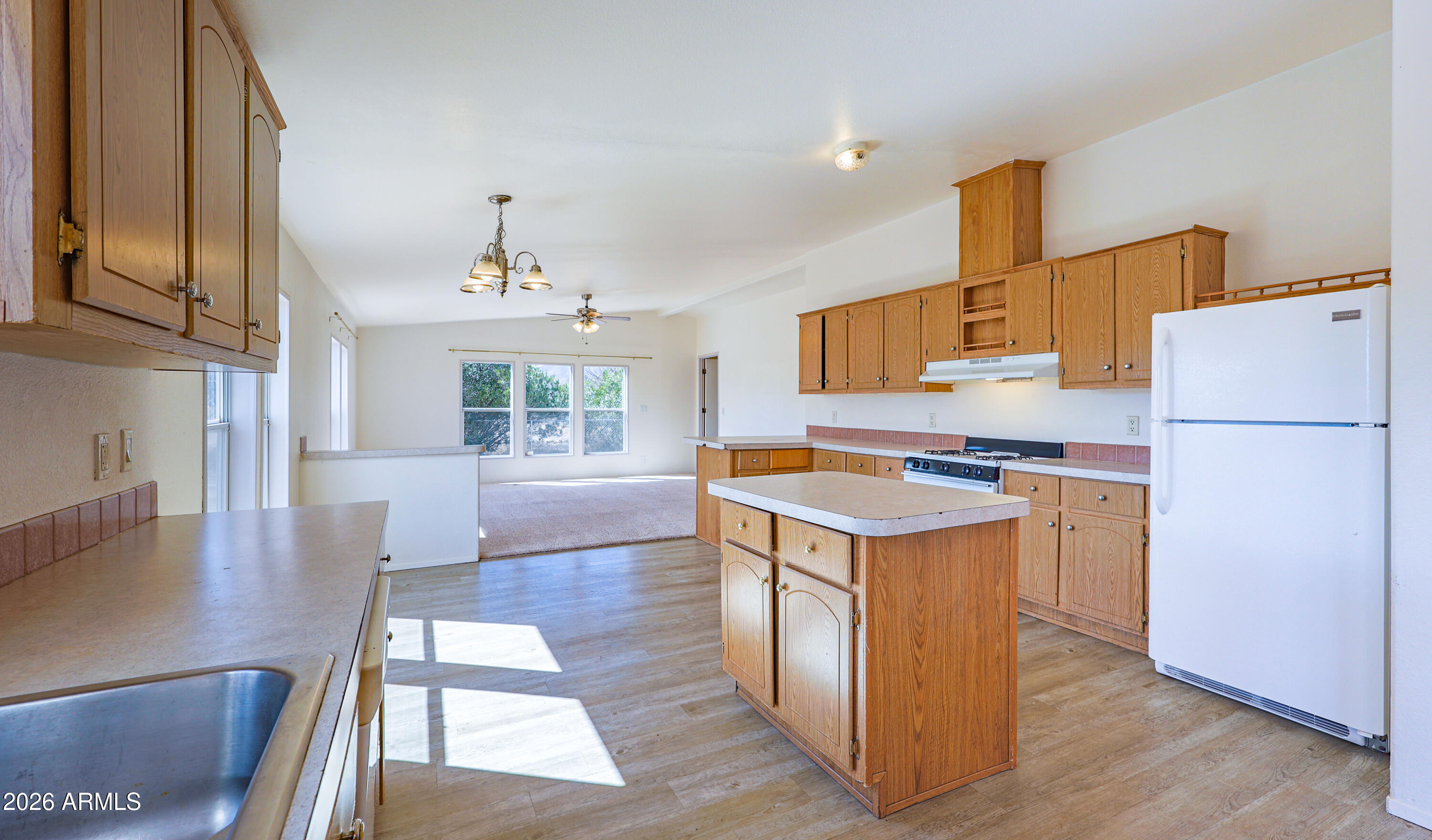 5144 Clearview Road Sierra Vista, AZ 85650 - Photo 13 of 32 a kitchen with a refrigerator a stove top oven a sink and dishwasher with wooden floor