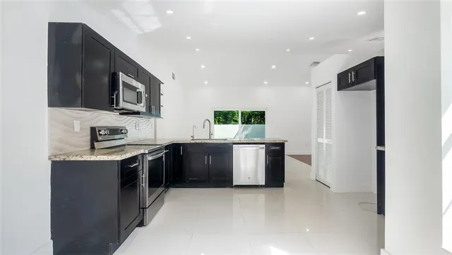 a kitchen with stainless steel appliances granite countertop a refrigerator and a stove top oven