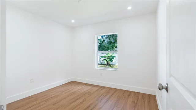 an empty room with wooden floor and window