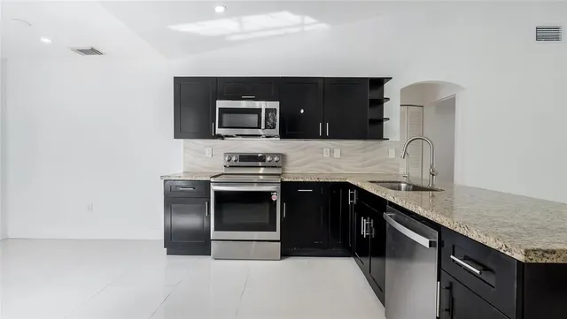 a kitchen with stainless steel appliances granite countertop a sink and stove top oven