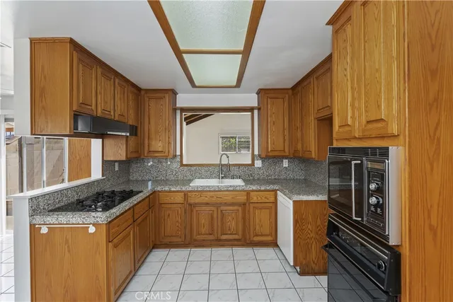 a kitchen with granite countertop a sink stove and refrigerator