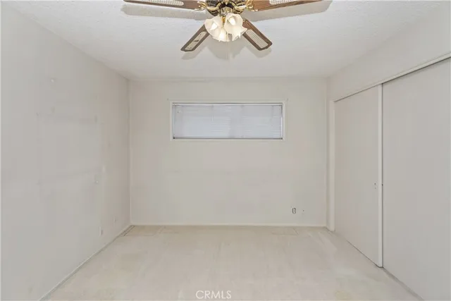 an empty room with a fan & a window