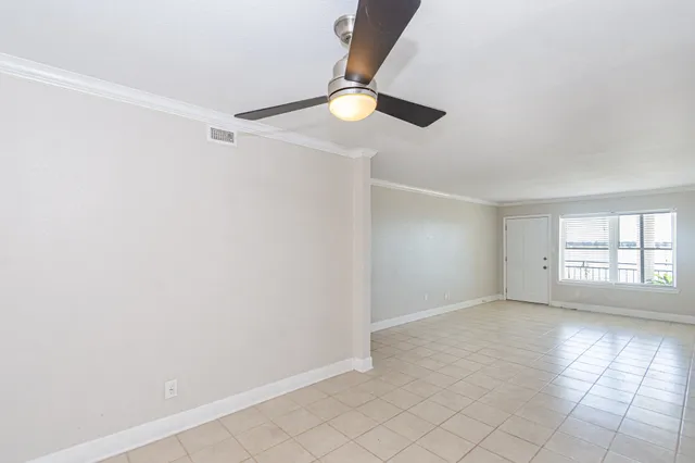 an empty room with windows and fan