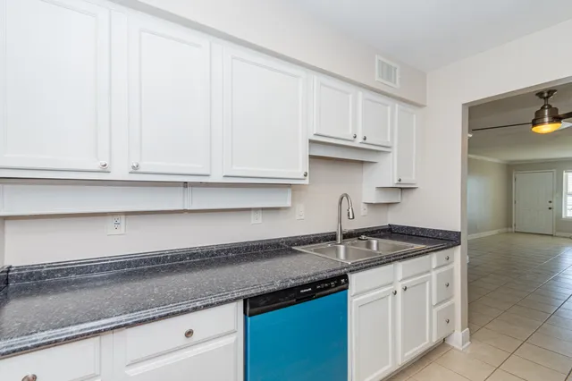 a kitchen with granite countertop white cabinets and a sink