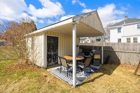 a view of a patio with table and chairs near a barbeque