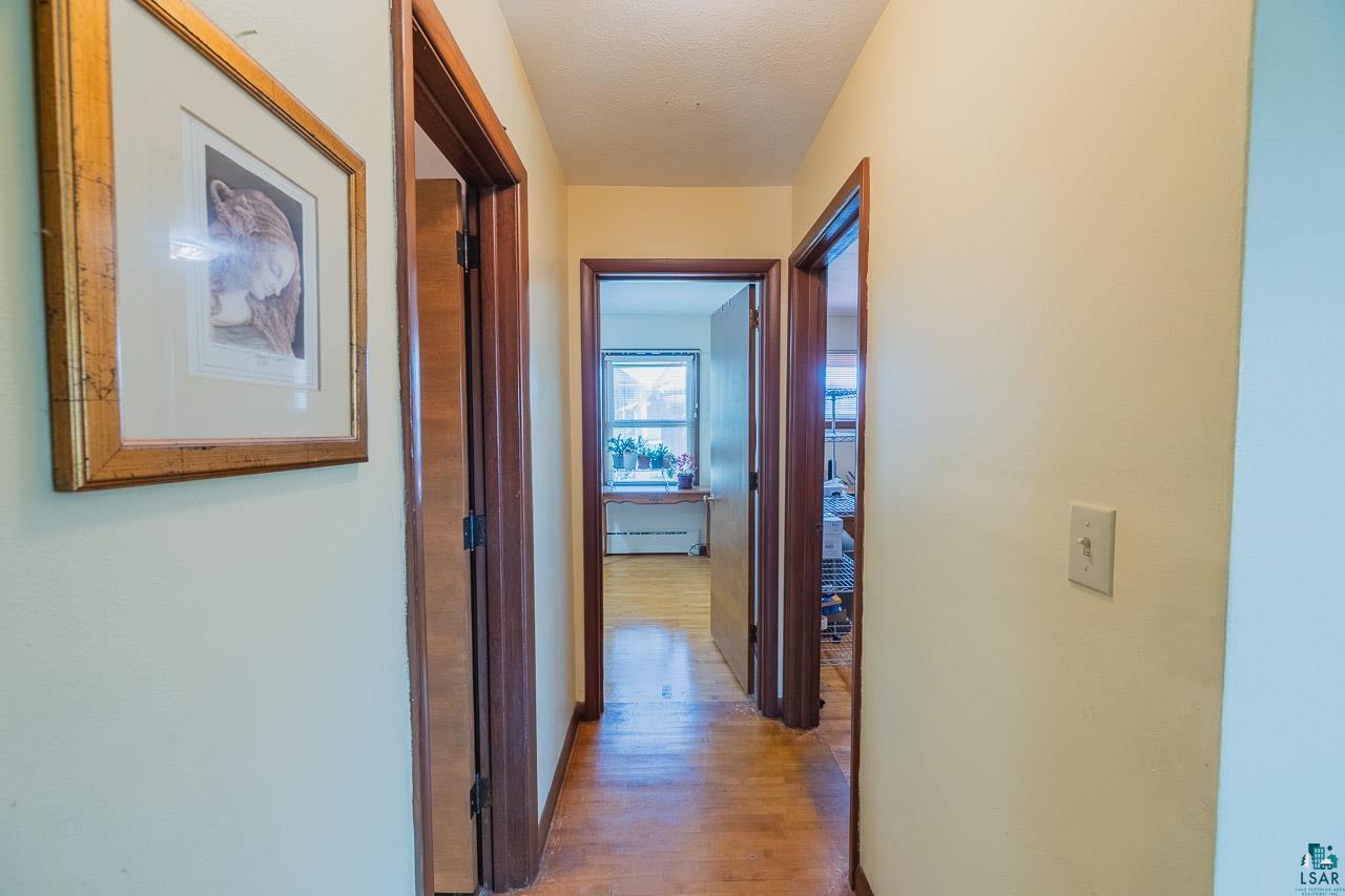101 2nd Avenue North Biwabik, MN 55708 - Photo 11 of 44 Hallway featuring light-toned wall paint, wood-finish flooring, and multiple doorways with dark wood trim