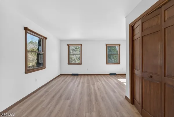 an empty room with wooden floor closet and windows