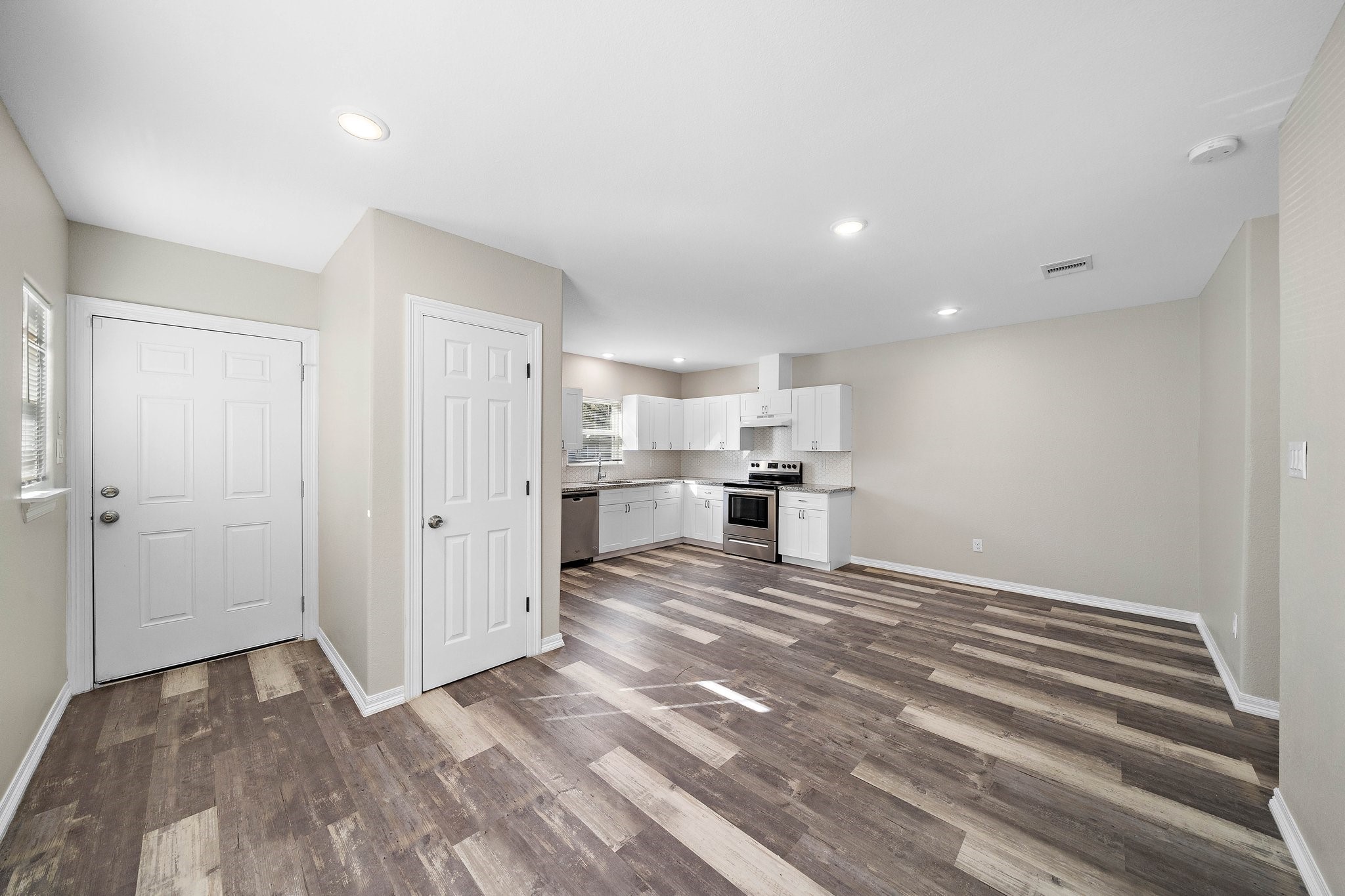 a view of kitchen and empty room with wooden floor