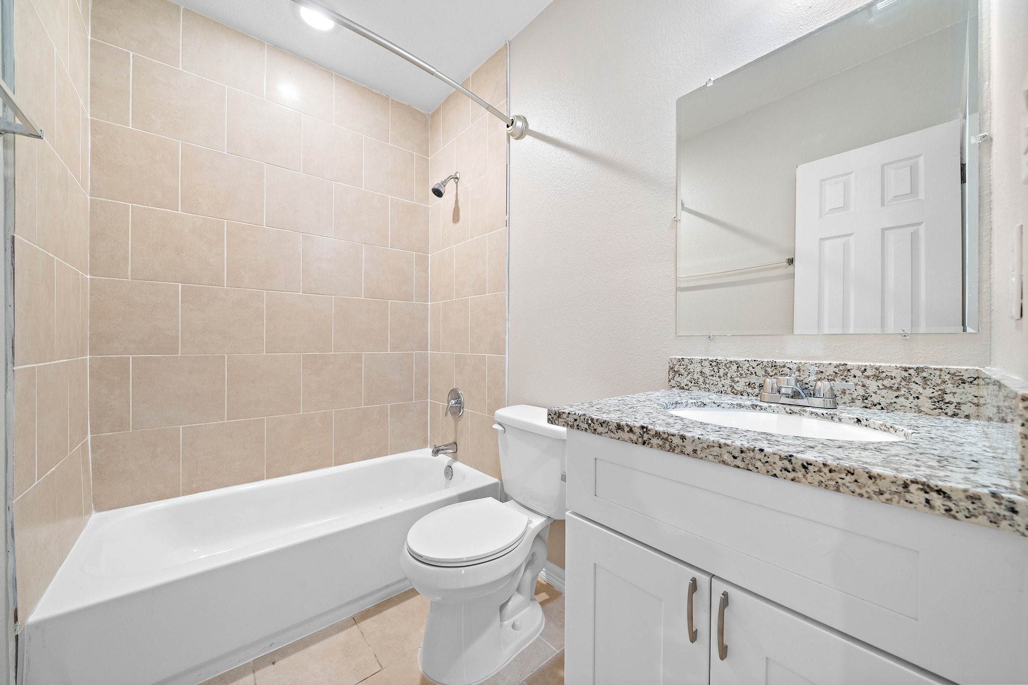 9118 Sandra Street, Unit B Houston, TX 77016 - Photo 8 of 10 a bathroom with a granite countertop toilet sink a mirror a bathtub and shower