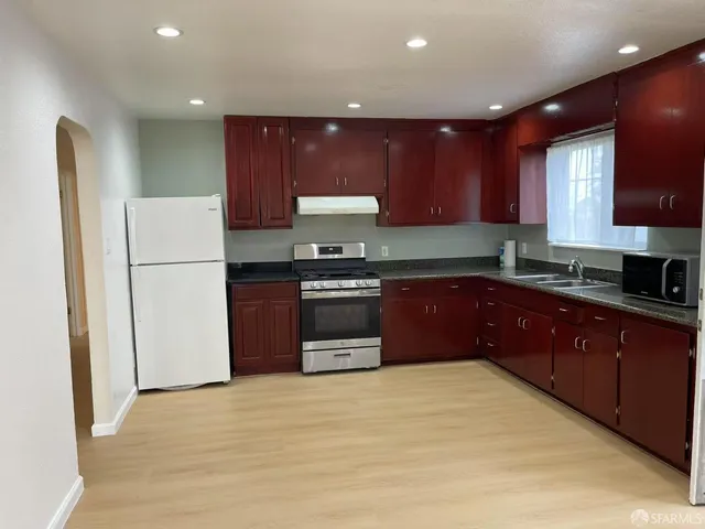 a kitchen with a refrigerator a stove top oven and wooden cabinets