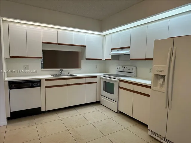 a kitchen with white cabinets appliances and a sink