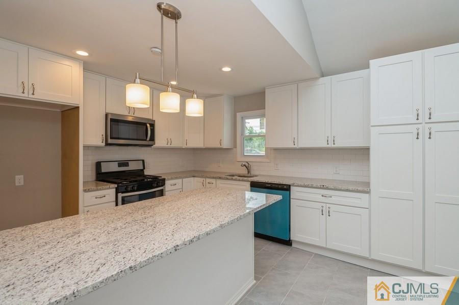 139 Tennent Road Morganville, NJ 07751 - Photo 3 of 15 a kitchen with kitchen island white cabinets appliances and a sink