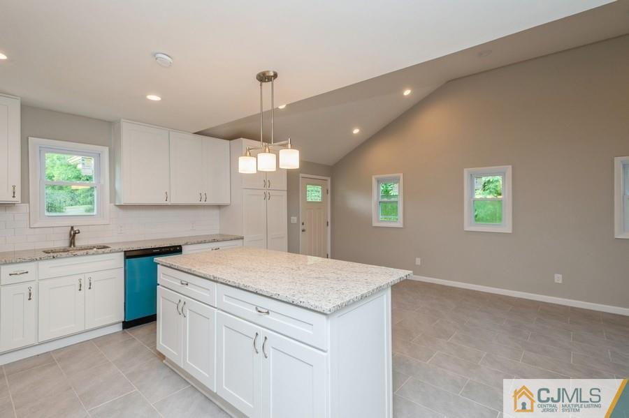139 Tennent Road Morganville, NJ 07751 - Photo 4 of 15 a kitchen with a sink dishwasher a stove a dining table and chairs with wooden floor