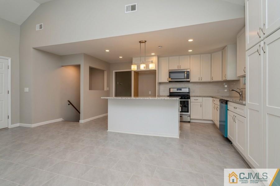 139 Tennent Road Morganville, NJ 07751 - Photo 5 of 15 a kitchen with stainless steel appliances granite countertop a stove top oven a sink and a refrigerator