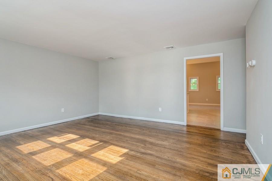 139 Tennent Road Morganville, NJ 07751 - Photo 10 of 15 an empty room with wooden floor and windows