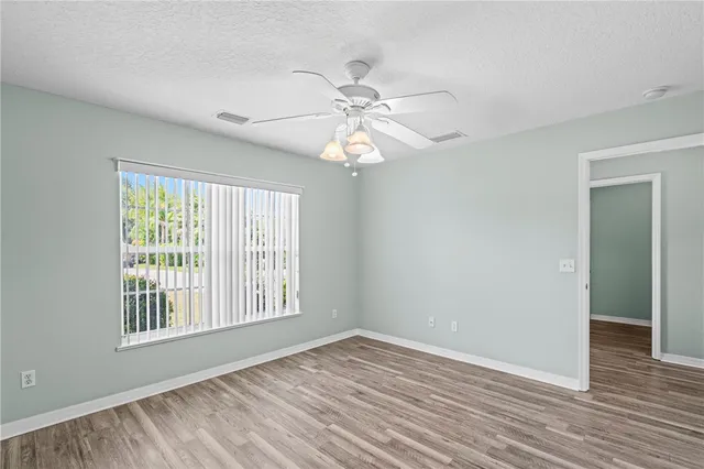 a view of an empty room with window and wooden floor