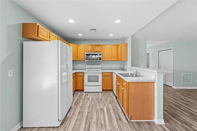 a kitchen with stainless steel appliances granite countertop a refrigerator a sink dishwasher and a stove with wooden floor