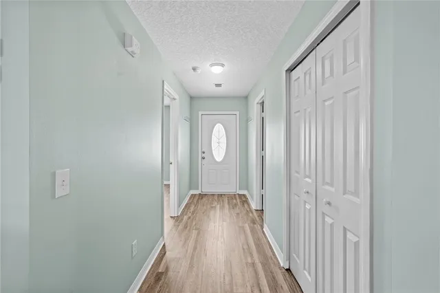 a view of a hallway with wooden floor and a bathroom