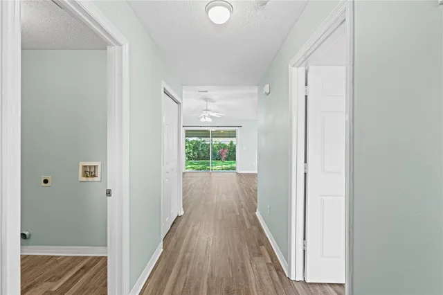 a view of a hallway with wooden floor and a bathroom