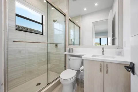 a bathroom with a granite countertop toilet sink and mirror