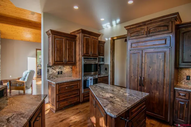 a kitchen that has a kitchen island wooden cabinets and stainless steel appliances