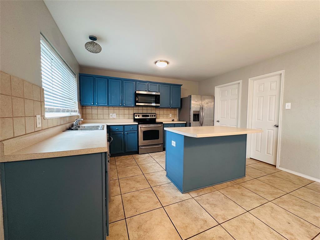 213 Spruce Trail Forney, TX 75126 - Photo 5 of 19 a kitchen with stainless steel appliances granite countertop a sink counter space cabinets and a large window