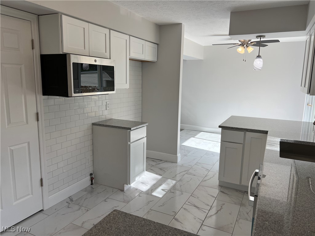 1279 Lander Road Cleveland, OH 44124 - Photo 7 of 37 Kitchen with baseboards, marble finish floor, ceiling fan, stainless steel microwave, and dark stone countertops