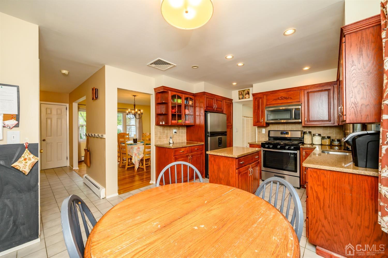 24 Clover Lane Randolph, NJ 07869 - Photo 12 of 59 a large kitchen with stainless steel appliances granite countertop a stove a sink dishwasher a dining table and chairs with wooden floor