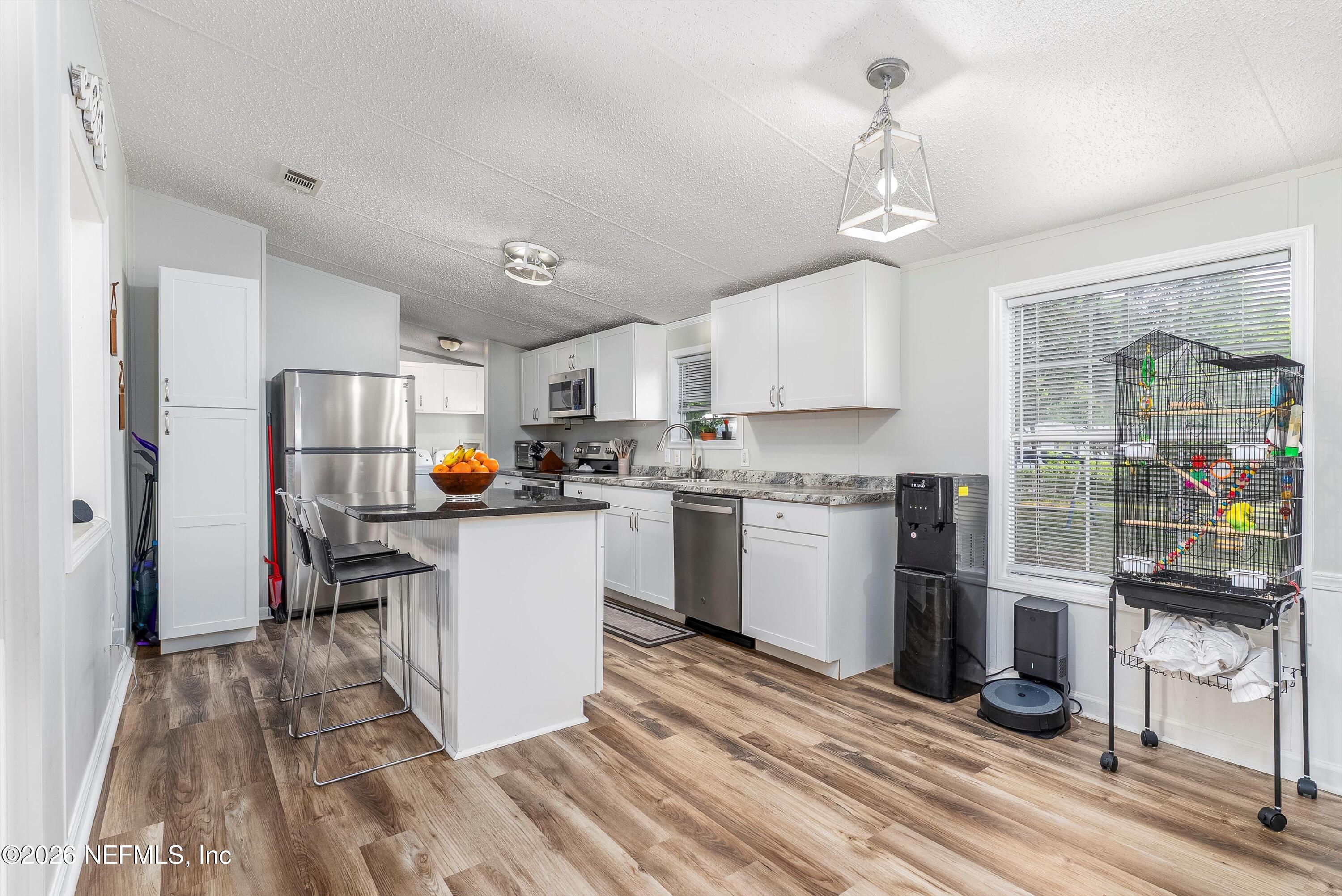 85246 Johnson Lane Yulee, FL 32097 - Photo 11 of 46 a kitchen with a refrigerator a stove top oven a sink dishwasher and white cabinets with wooden floor