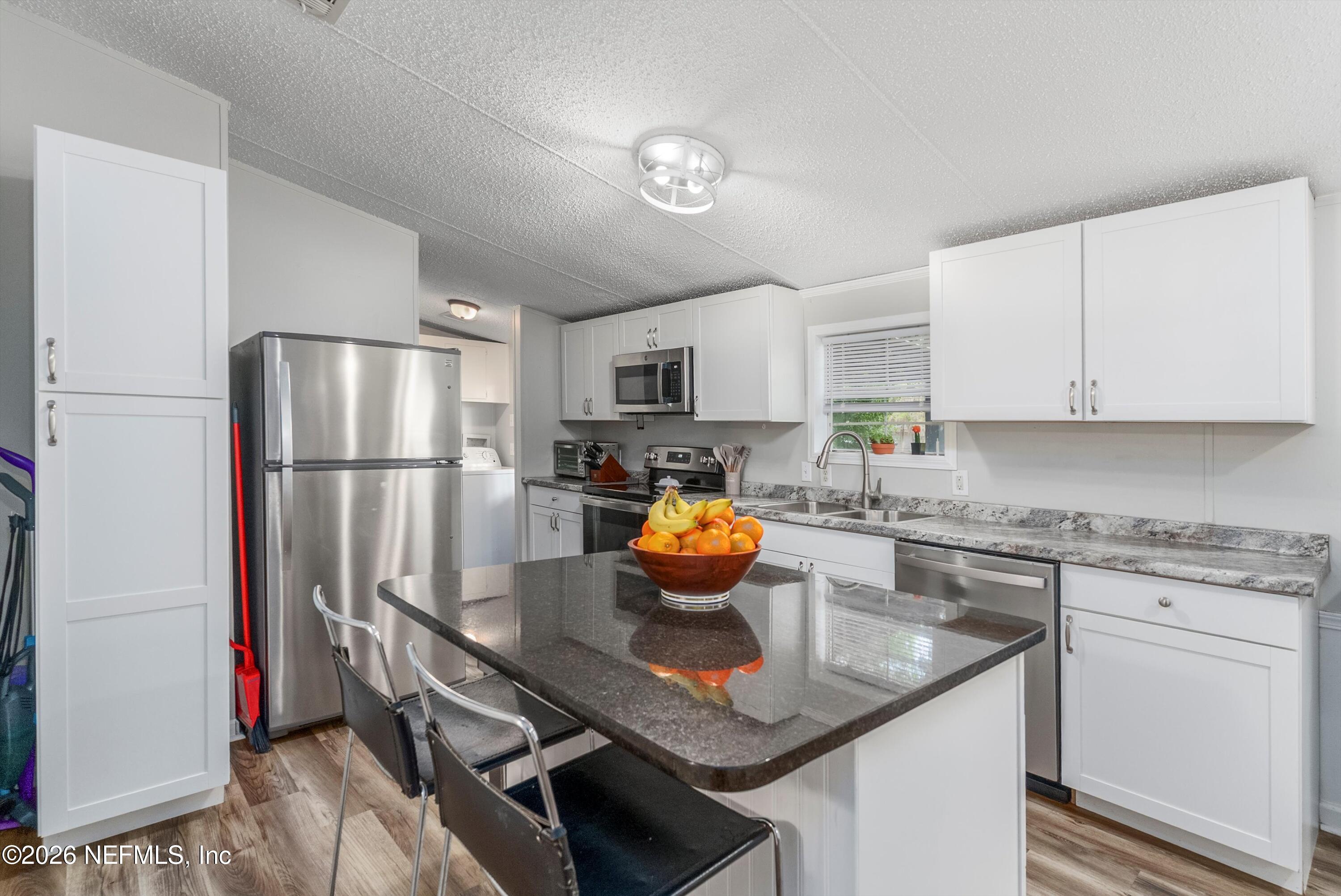 85246 Johnson Lane Yulee, FL 32097 - Photo 13 of 46 a kitchen with stainless steel appliances granite countertop a refrigerator a stove a sink dishwasher and a refrigerator with wooden floor