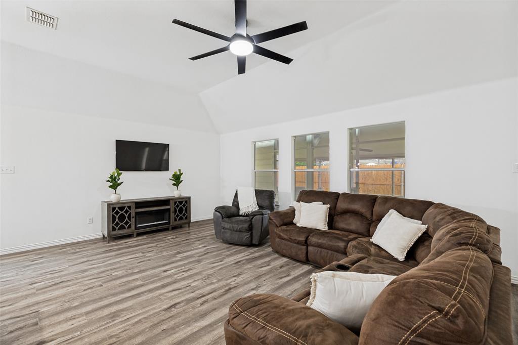 4305 Ridgewood Road Melissa, TX 75454 - Photo 6 of 26 Vaulted ceiling living area featuring wood-finish flooring, a contemporary ceiling fan, and multiple windows
