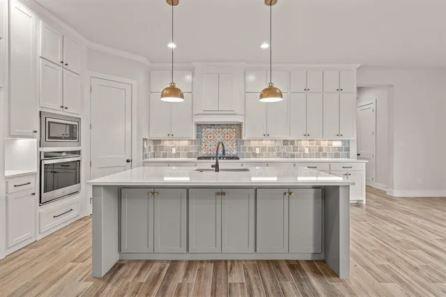 a kitchen with kitchen island granite countertop a sink cabinets and stainless steel appliances