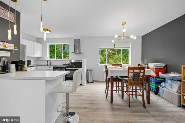 a kitchen with stainless steel appliances granite countertop wooden floor dining table and chairs