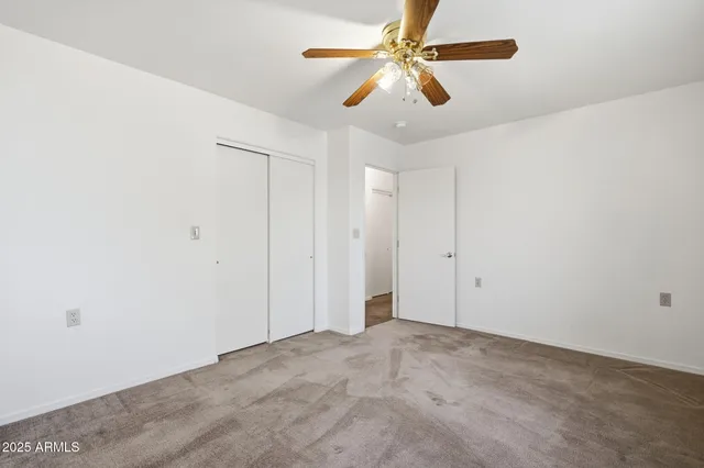 an empty room with a window and a fan