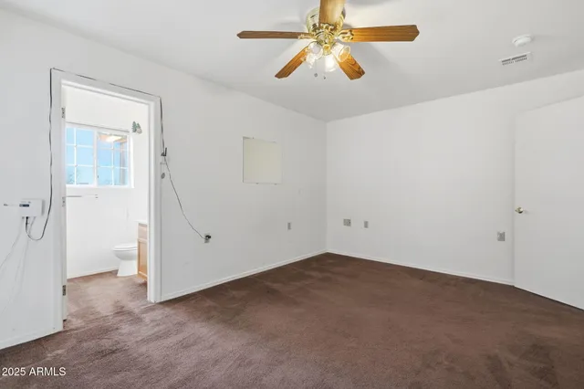 a view of an empty room with window and a kitchen