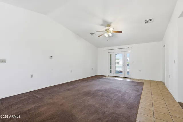 an empty room with chandelier fan and windows