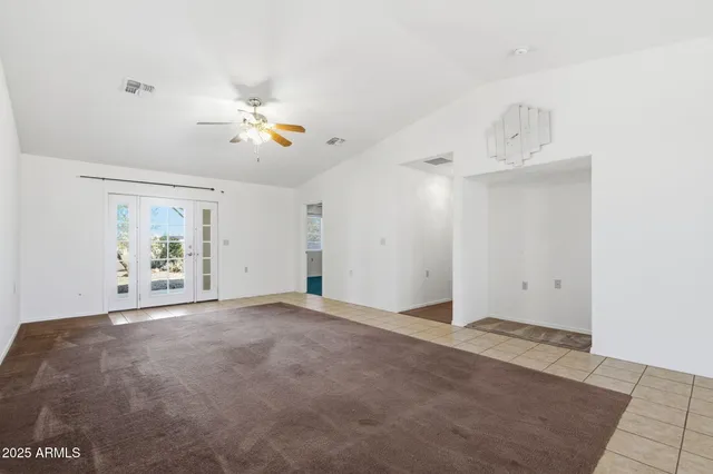 an empty room with fan and view of a bathroom