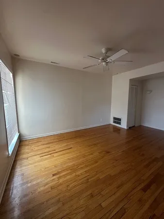 a view of empty room with wooden floor and fan