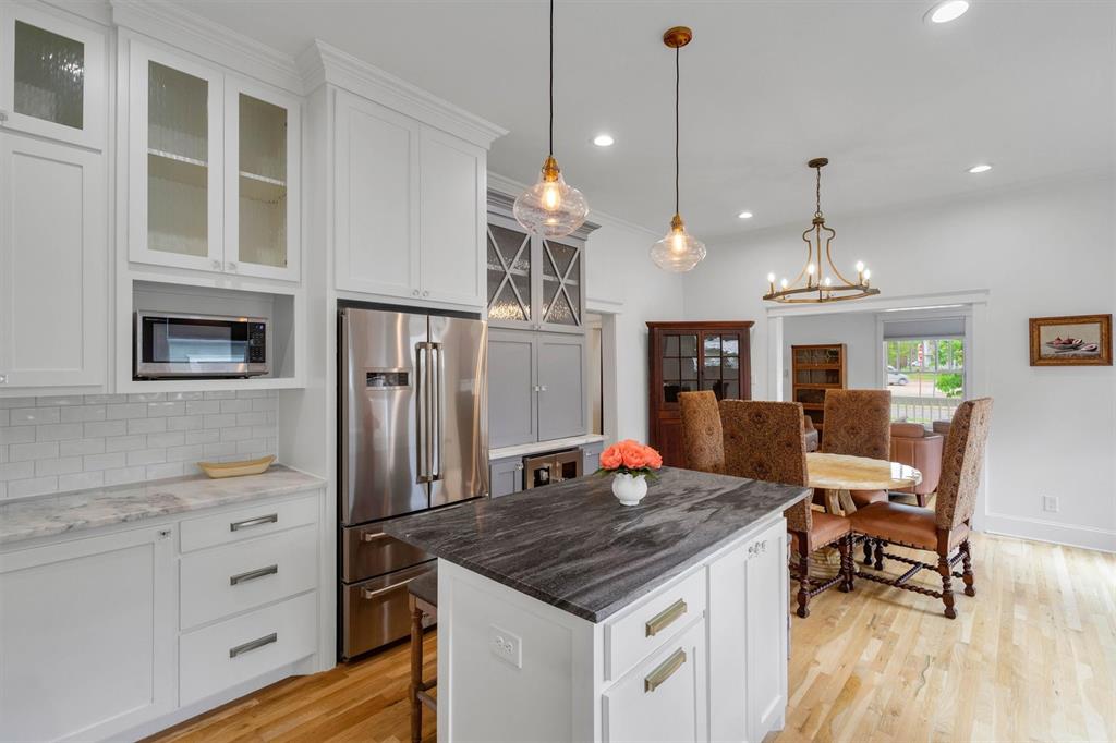 5727 Victor Street Dallas, TX 75214 - Photo 16 of 40 a kitchen with stainless steel appliances kitchen island granite countertop a stove a refrigerator a kitchen island a dining table and chairs with wooden floor